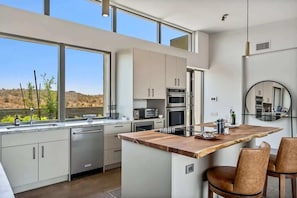 Cocina moderna con una isla grande, electrodomésticos de acero inoxidable y vistas al desierto.