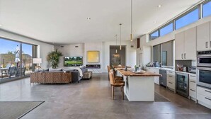 A spacious living area with a large sofa, a dining area with chairs, a kitchen with modern appliances, and large windows offering views. - Paradise Canyon-Heated Pool-Mountain View-Estate 2 (Fort Mcdowell)
