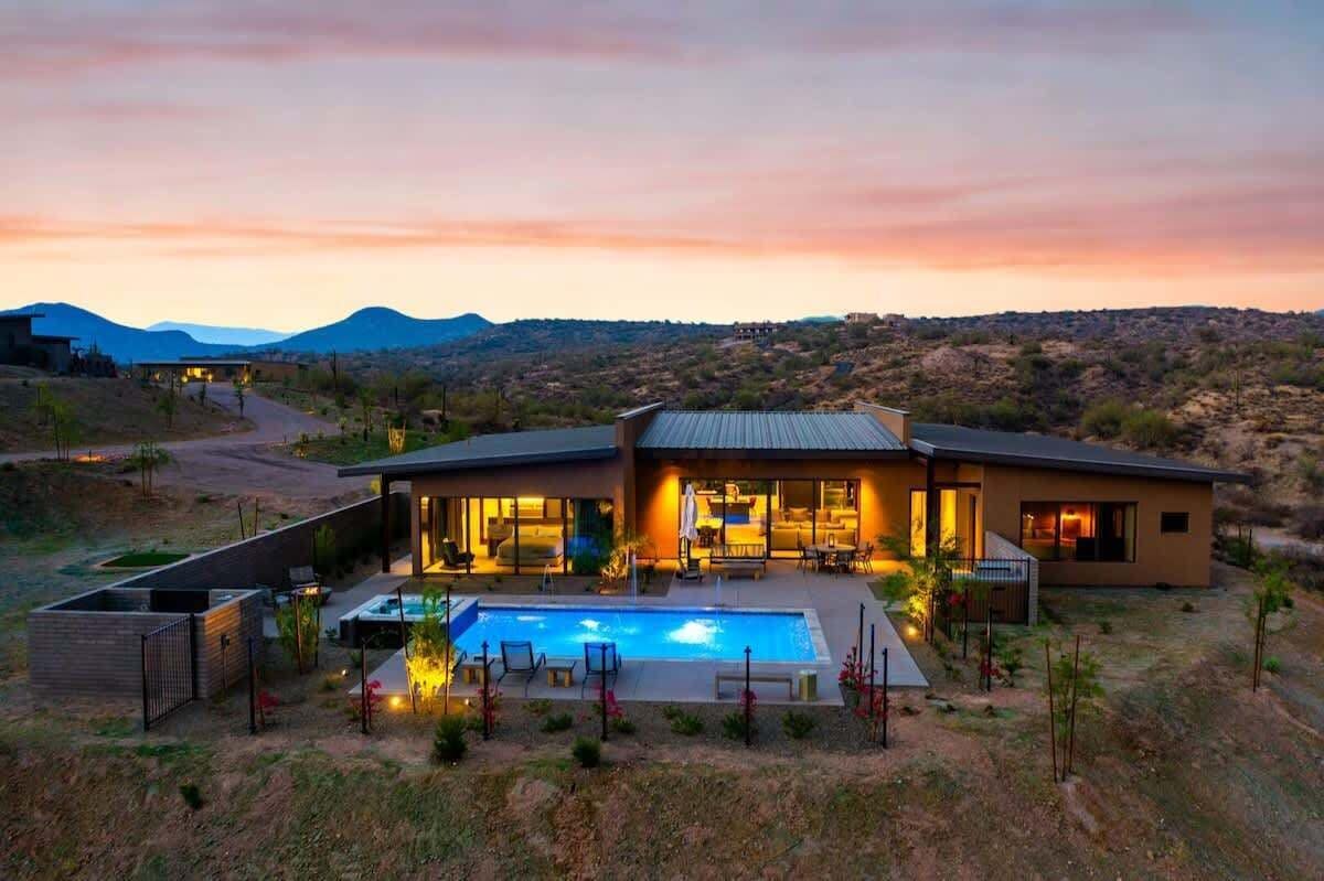 Une maison moderne dotée d’une piscine, de grandes fenêtres et offrant une vue sur le paysage environnant.