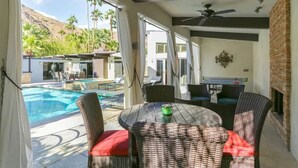Un espace aménagé au bord de la piscine, avec des meubles en osier, une table et un ventilateur de plafond.