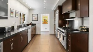Une cuisine moderne avec des meubles de couleur sombre, une cuisinière en acier inoxydable et un lave-vaisselle.