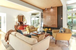 Uma sala de estar moderna com lareira, sofá, poltronas e uma mesa de centro.