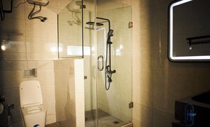 A modern bathroom with a glass-enclosed shower, a toilet, and a sink. - Harzock hotel (Abuja)