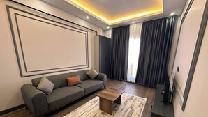 Una sala de estar moderna con un sofá gris, una mesa de centro de madera y una obra de arte grande enmarcada en la pared.