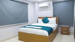 A neatly made bed with a wooden headboard, a small bedside table, and a wall-mounted air conditioner. - Single Room in Secure Apartment – Akoka Yaba Lagos (Yaba)