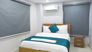 A neatly made bed with white and teal bedding, a wooden headboard, and a teal pillow. There is a small wooden nightstand beside the bed. - Single Room in Secure Apartment – Akoka Yaba Lagos (Yaba)
