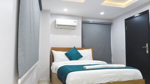 A bedroom with a bed, a window, an air conditioning unit, and a door. - Single Room in Secure Apartment – Akoka Yaba Lagos (Yaba)