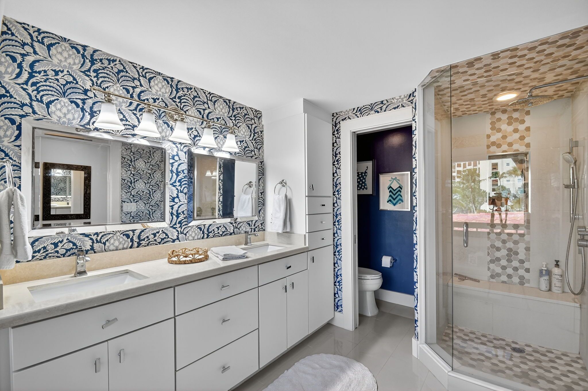 A bathroom with a large mirror, a sink, and a shower.