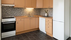 Een keuken met houten kastjes, een witte vaatwasser, een fornuis en een koelkast.