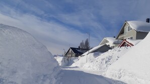 Een besneeuwde weg met huizen aan beide zijden.