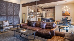 Un salon moderne avec un canapé en cuir, une table basse et un coin repas comprenant une table et des chaises.