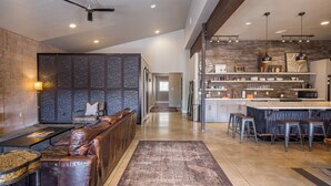 Une cuisine moderne dotée d’un bar, d’un mur recouvert de pierres apparentes et d’un coin salon avec des canapés en cuir.
