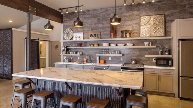 Une cuisine moderne dotée d’un grand îlot central, de tabourets de bar et d’un pare-feu en pierre.