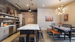 Une cuisine moderne dotée d’un grand îlot central, de tabourets de bar et d’un coin repas avec une table et des chaises en bois.