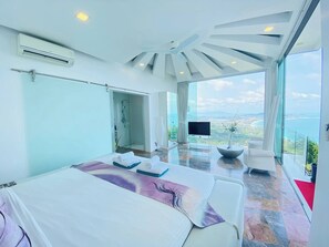 Une chambre d’hôtel moderne dotée d’un grand lit, d’une télévision, d’un balcon avec vue et d’un espace douche.