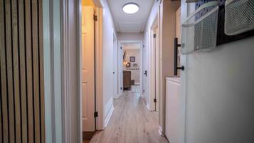 A hallway with wooden flooring, white walls, and a ceiling light.