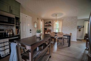 A kitchen with a central island, wooden cabinets, and a dining area with chairs and a table.