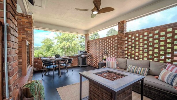 Un patio techado con comedor, una parrilla y una zona de estar con una chimenea.