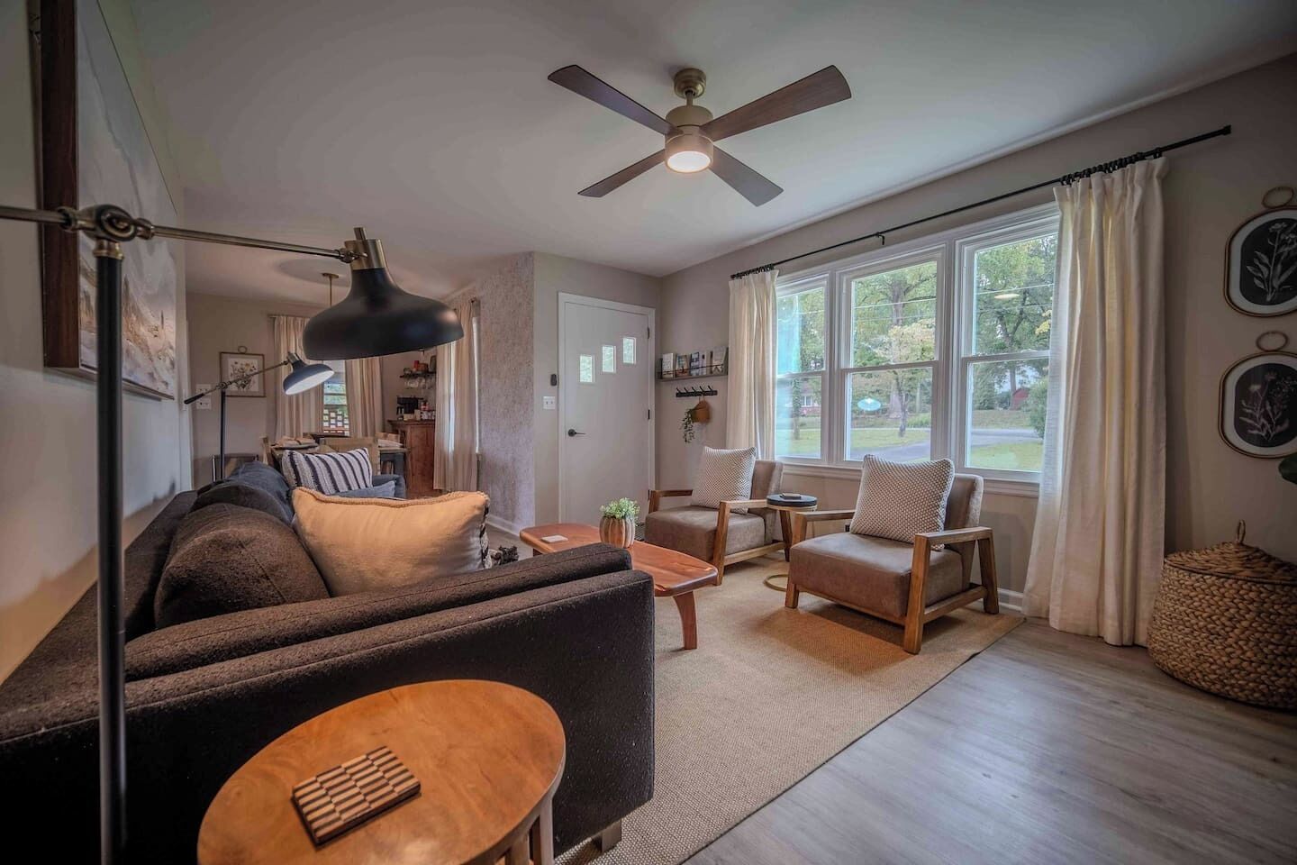 A living room with a sofa, armchairs, a coffee table, and a ceiling fan.