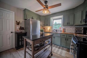 A kitchen with a refrigerator, oven, and a ceiling fan.
