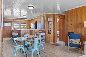 A wooden interior with a dining area, kitchen, and seating. - Holliday Haven #200 - Oceanfront Escape in Topsail Beach, Sleeps 9! (Topsail Beach)