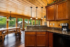 A kitchen with wooden cabinets, granite countertops, and pendant lights.