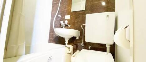 Un baño con un lavamanos blanco, un inodoro y un espejo en una pared de mármol.