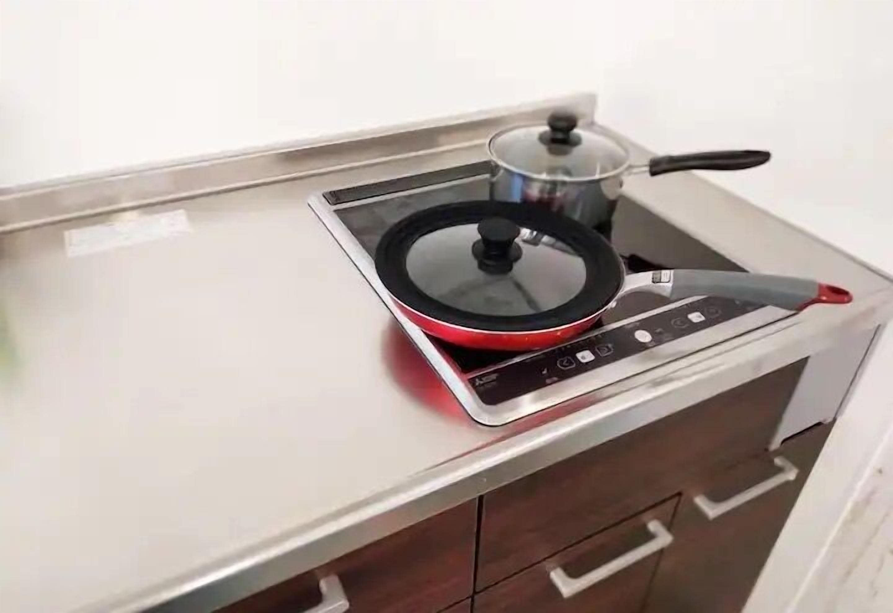 A compact kitchen with a built-in induction cooktop and a pot on it.