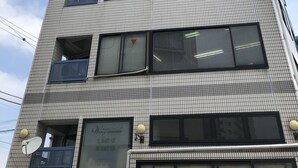 Un edificio de varios pisos con fachada de tejas, múltiples balcones y ventanas grandes.