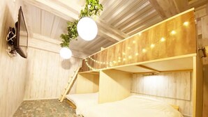 Una habitación con literas, paredes de madera, una lámpara colgante y una planta pequeña.