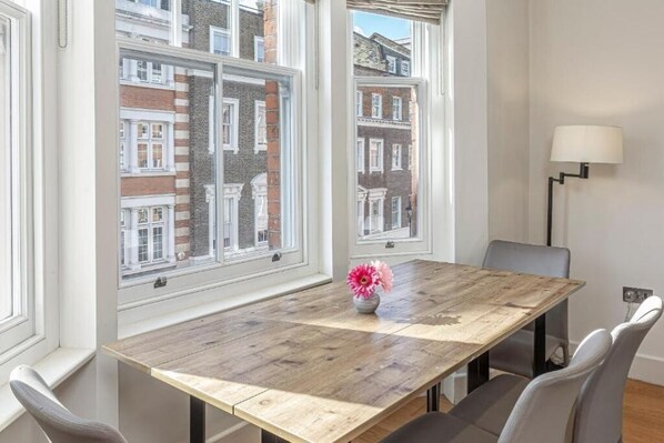A dining area with a wooden table, four chairs, and a vase with flowers.