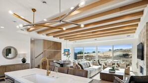 A modern kitchen with a marble island, wooden beams, and a large window overlooking a scenic landscape. - Luxury Retreat 12 miles from Park City - Ameyalli (Midway)