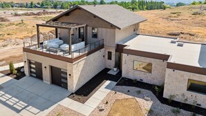 A modern two-story house with a covered patio, a garage, and a view of the surrounding landscape. - Luxury Retreat 12 miles from Park City - Ameyalli (Midway)