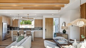 A modern kitchen with wooden cabinets, a dining area with a wooden table, and a living room with a sofa and a rug. - Luxury Retreat 12 miles from Park City - Ameyalli (Midway)
