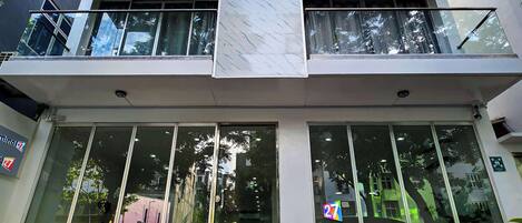 Un edificio moderno con una columna central de mármol, amplias ventanas de vidrio y un balcón con barandillas.