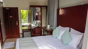 Une chambre d’hôtel avec un lit, un bureau, une chaise et un miroir.