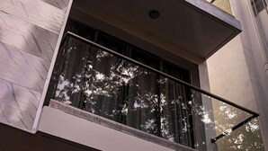 Un immeuble à plusieurs étages doté d’une architecture moderne, avec des balcons pourvus de garde-corps en verre et de grandes fenêtres.