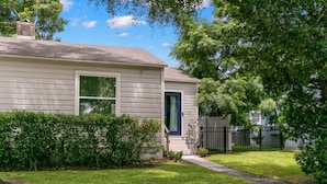 A single-story house with a front yard, a small pathway leading to the front door, and a black metal fence in the background. - NEW Soho Sanctuary - Gorgeous Apartment Steps to S Howard Ave With Fenced Yard (Tampa)