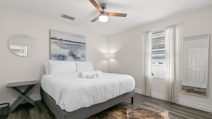 A bedroom with a bed, a ceiling fan, a painting, a mirror, a lamp, and a door. - NEW Soho Sanctuary - Gorgeous Apartment Steps to S Howard Ave With Fenced Yard (Tampa)
