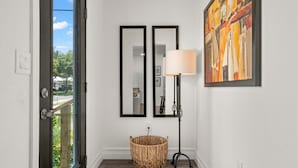 A hallway with a wicker basket, two mirrors, a floor lamp, and a painting on the wall. - NEW Soho Home - Perfect Space for Families (Tampa)