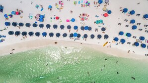 Une vue aérienne d’une plage où l’on voit de nombreux parasols et des gens.