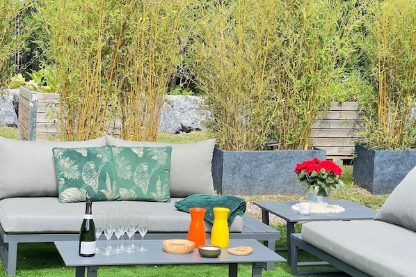An outdoor seating area with a sofa, two tables, and a backdrop of bamboo plants. - Hôtel Particulier d'Exception Champagne Experience - 5 minutes from Reims (cernay les reims)