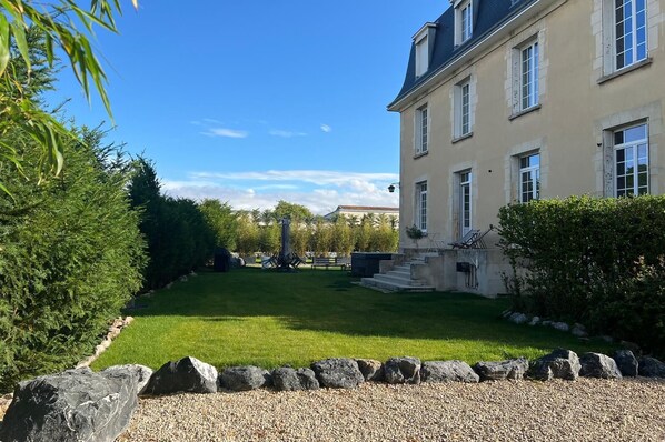 A well-maintained garden with a lawn, a stone pathway, and a building with multiple windows and a balcony.
