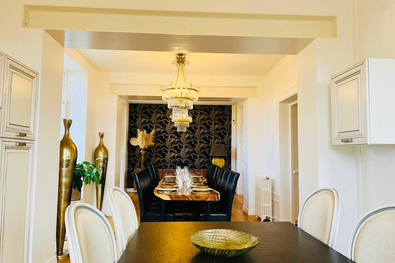 Un coin repas agrémenté d’un lustre, d’un mur à motifs et d’un radiateur.