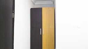 A wardrobe with two doors, one dark and one light, in a room with white walls and a white ceiling. - Clean Single Room in Lagos Suitable for Getaway and Remote Work (Yaba)