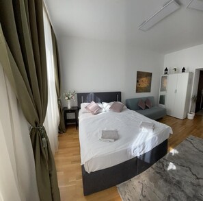 Quarto moderno com uma cama grande, mesa de cabeceira, cômoda e sofá.