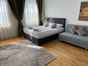 Um quarto com cama, sofá, tapete e um quadro na parede.