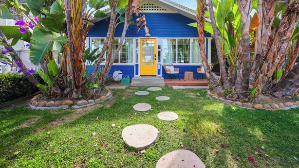 A house with a blue exterior, a yellow door, and a front yard with stepping stones and tropical plants. - Private 3 Bed House in North Park • Work, Yard, EV (San Diego)