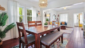 A dining area with a wooden table, chairs, a bench, and a hanging light fixture. - Private 3 Bed House in North Park • Work, Yard, EV (San Diego)