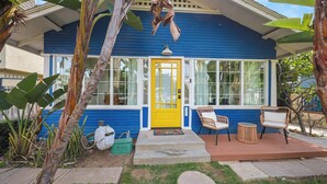 A house with a yellow door, large windows, and a porch with chairs and a table. - Private 3 Bed House in North Park • Work, Yard, EV (San Diego)